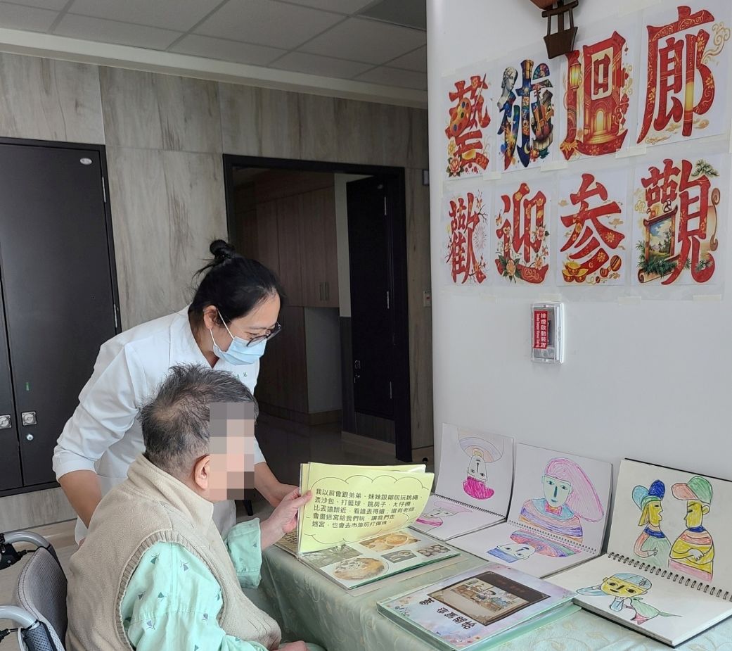 邱佳慧護理長（站立者）與住民長者欣賞藝術迴廊繪畫畫冊。